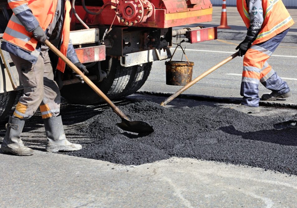 The working team renews a portion of asphalt with shovels in road construction